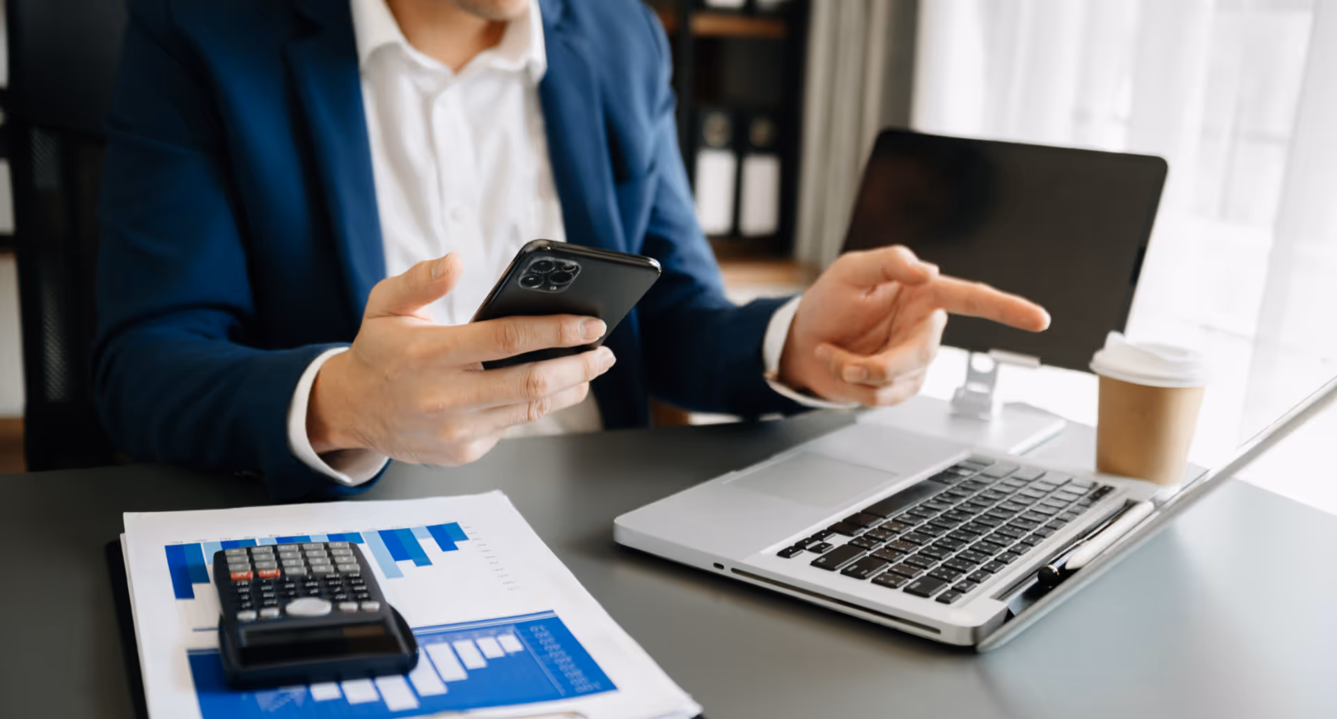 Business accountant reviewing finances on a laptop and phone